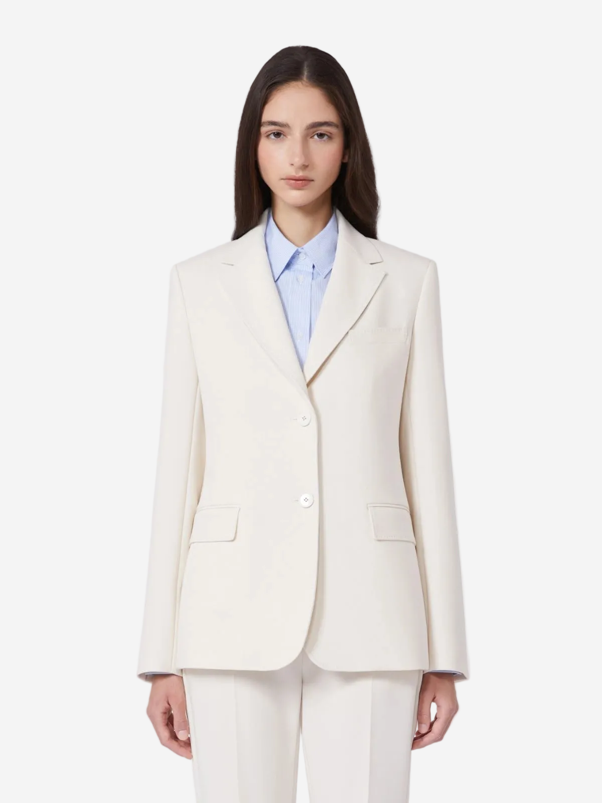 Woman wearing a cream blazer over a light blue shirt on a white background