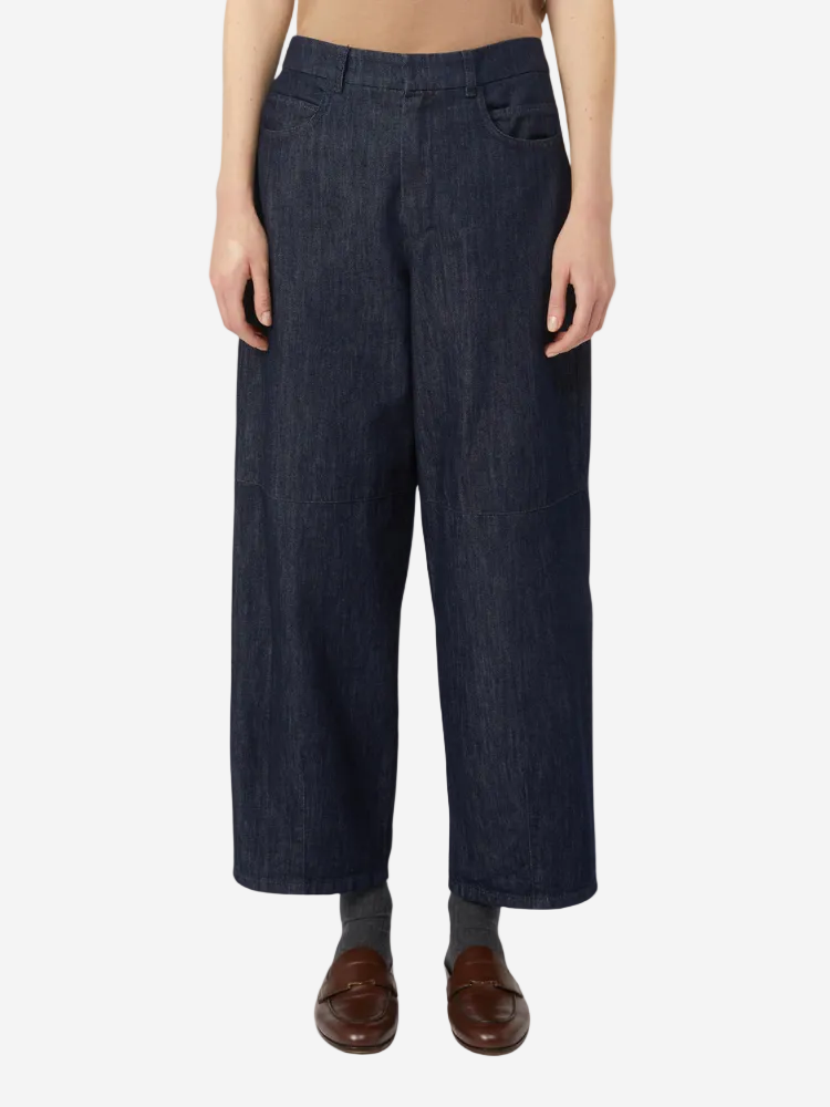 Person wearing dark blue wide-leg jeans on a white background