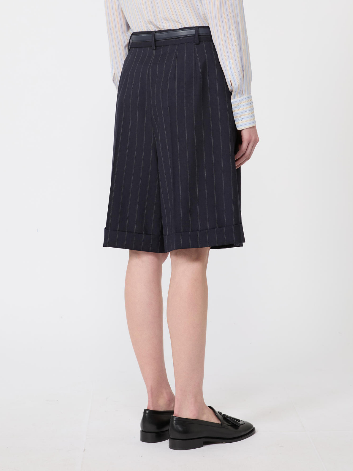 Person wearing a navy pinstripe skirt on a white background