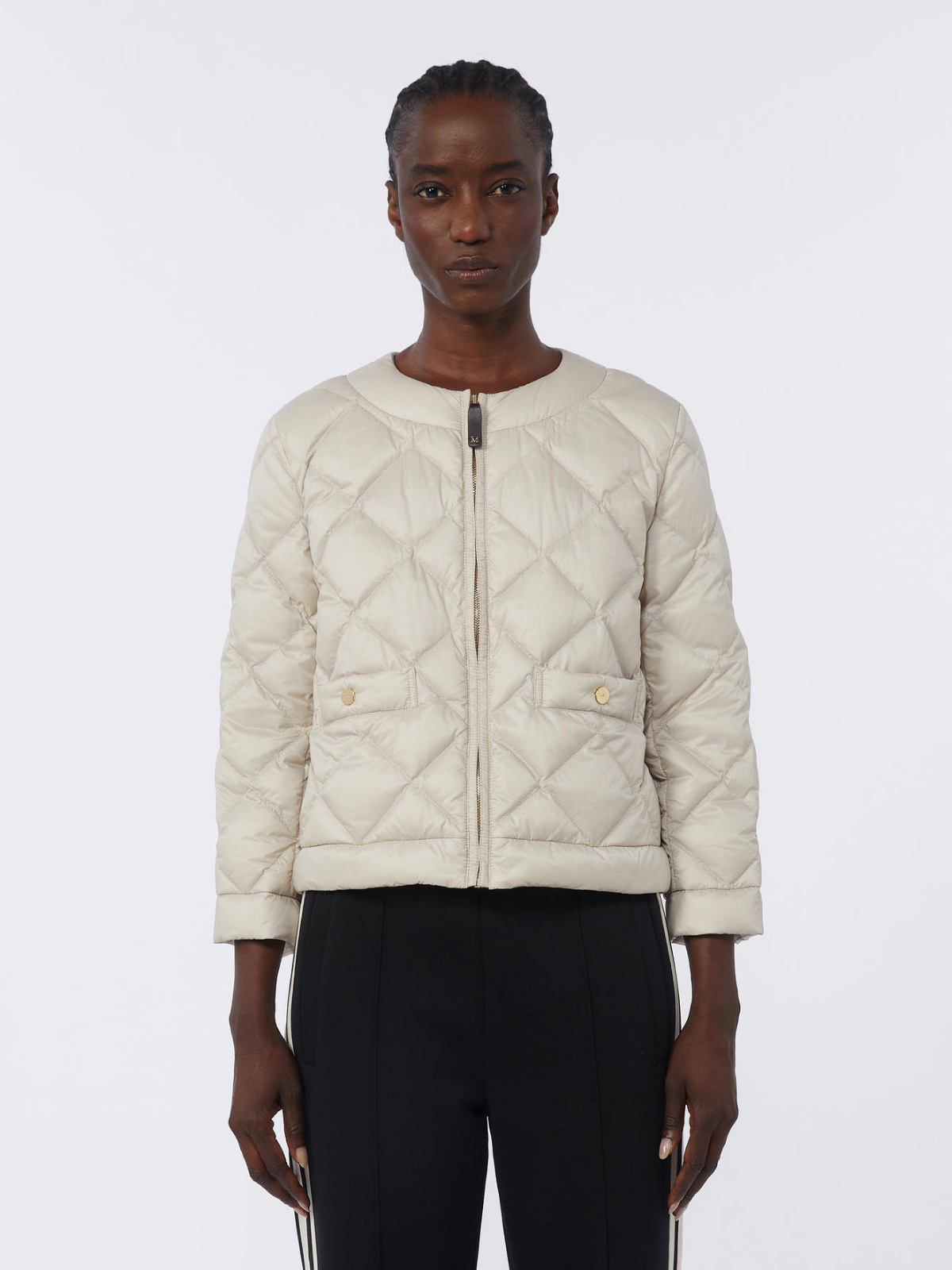 Person wearing a beige quilted jacket on a white background