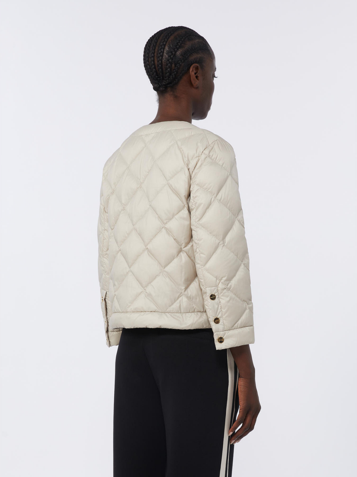 Person wearing a beige quilted jacket on a white background