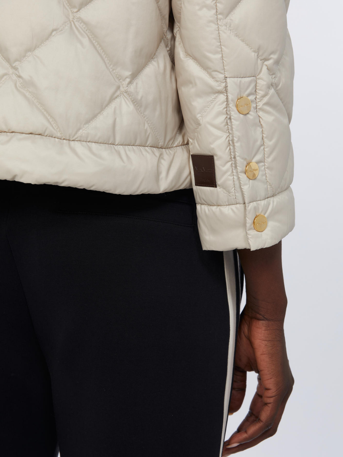 Close-up of a beige quilted jacket with buttons on a white background