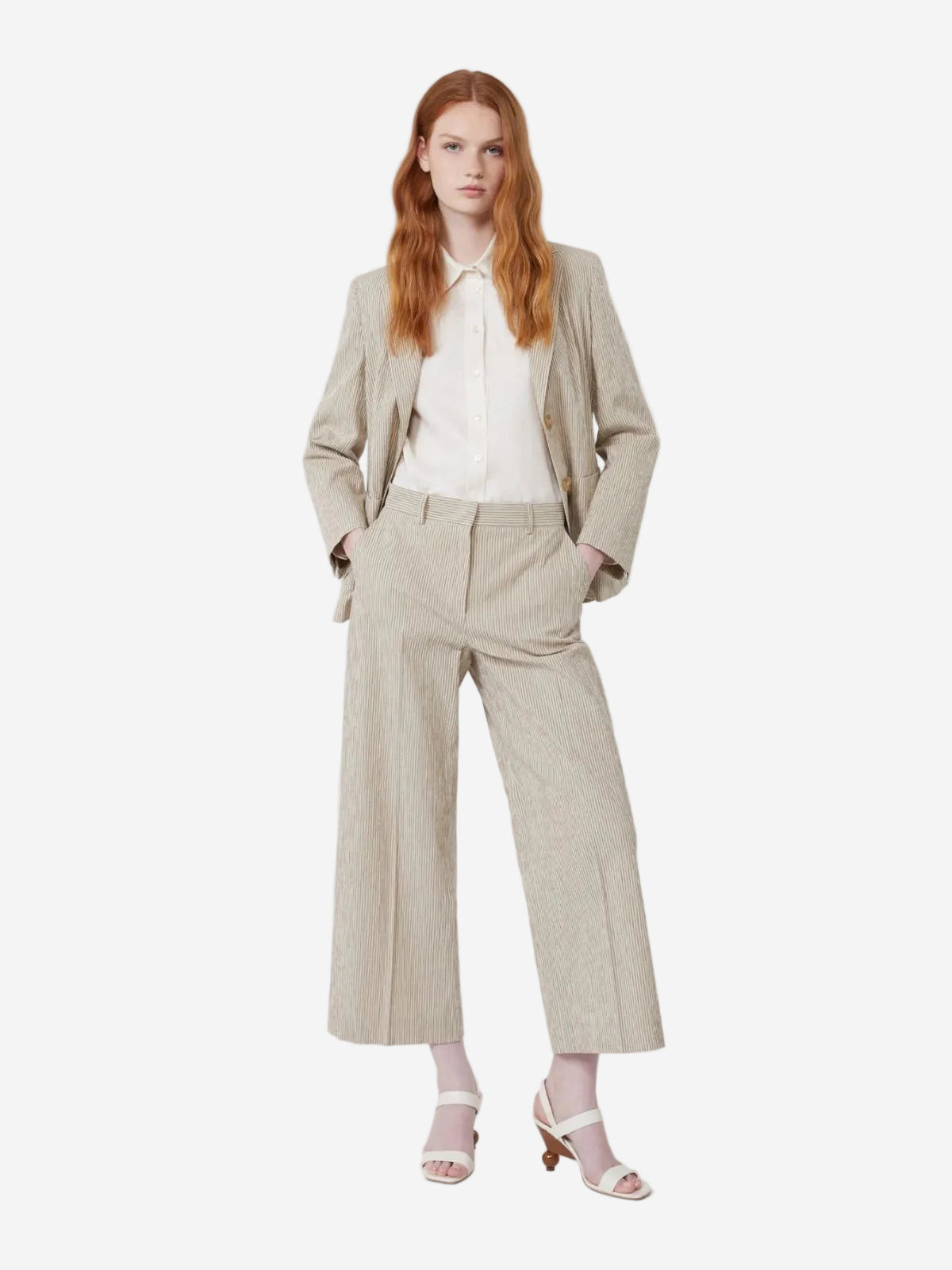 Woman wearing a beige suit with a white shirt on a light gray background, Available at Christensen Copenhagen