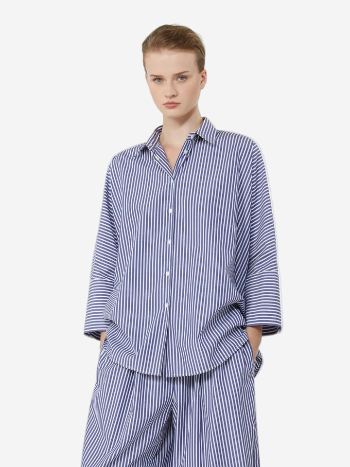 Person wearing a blue and white striped pajama set on a light gray background