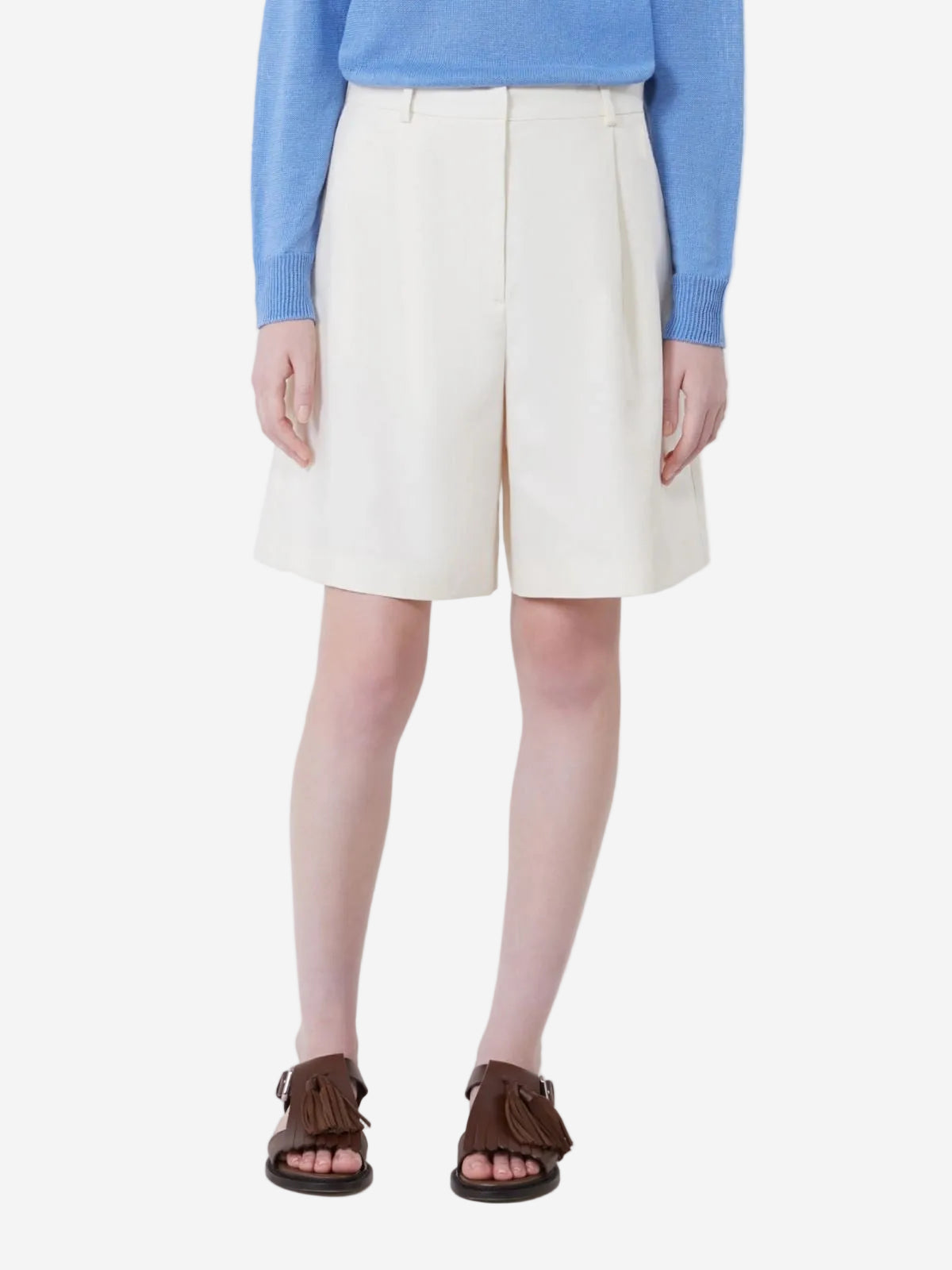 Person wearing a blue sweater, white shorts, and brown sandals on a white background
