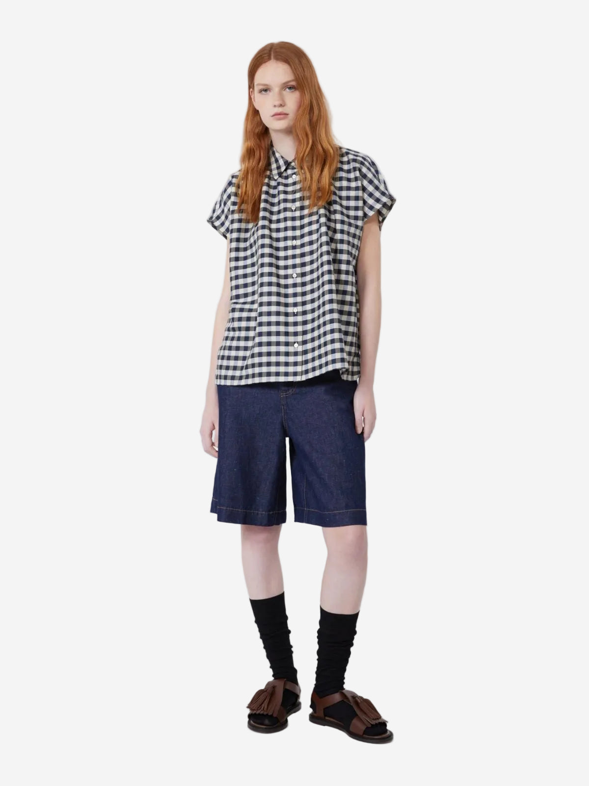 Person wearing a checkered shirt and denim shorts on a white background, stocked at Christensen Copenhagen.