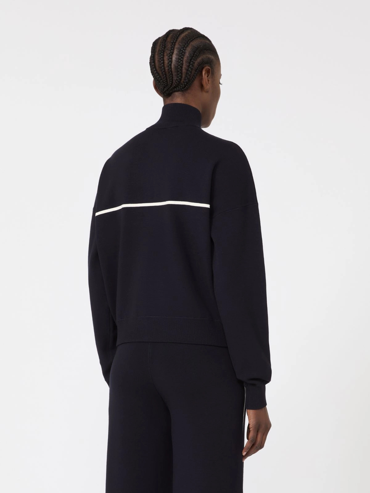 Person wearing a black tracksuit with a white stripe on a white background