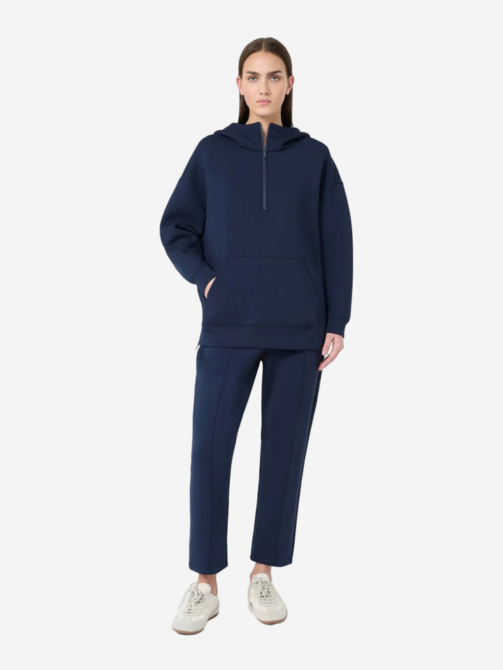 Person wearing a navy blue hoodie and pants on a white background