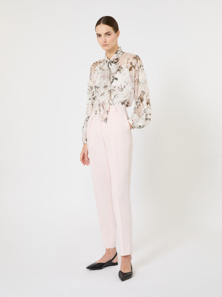 Woman wearing a floral blouse and light pink pants on a white background