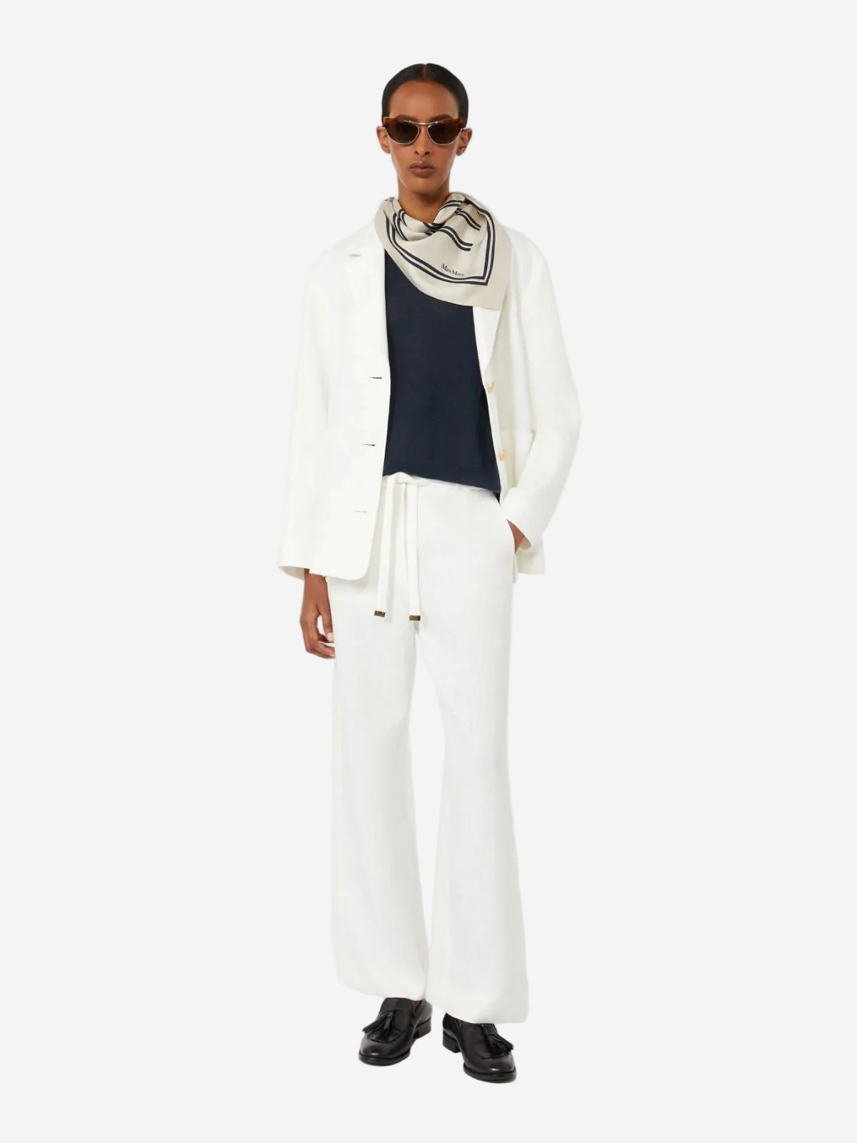 Person wearing a white outfit with a navy top and black shoes on a white background