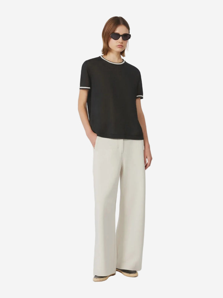 Person wearing a black t-shirt and white pants on a white background