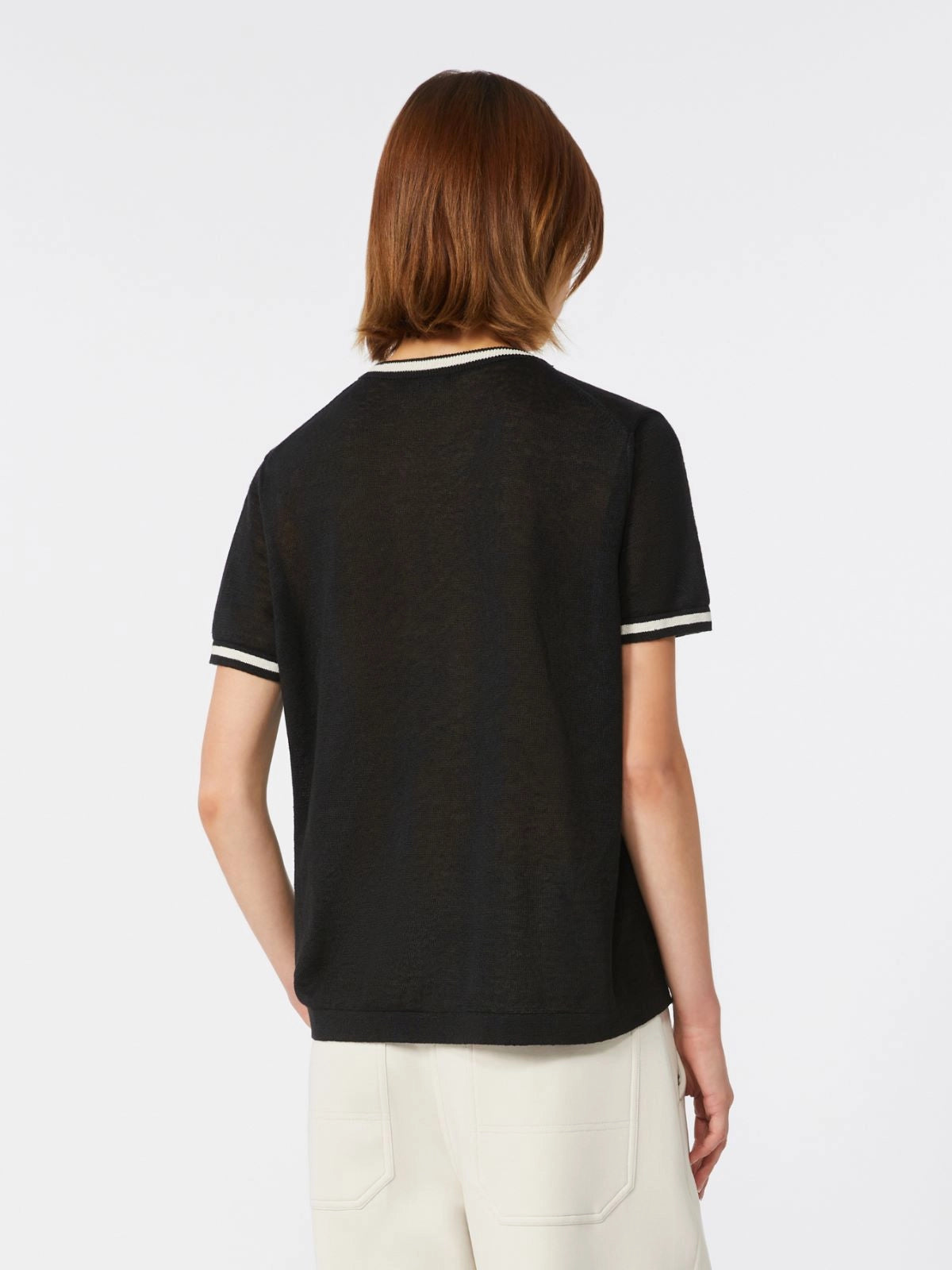 Person wearing a black t-shirt with white trim on a plain background