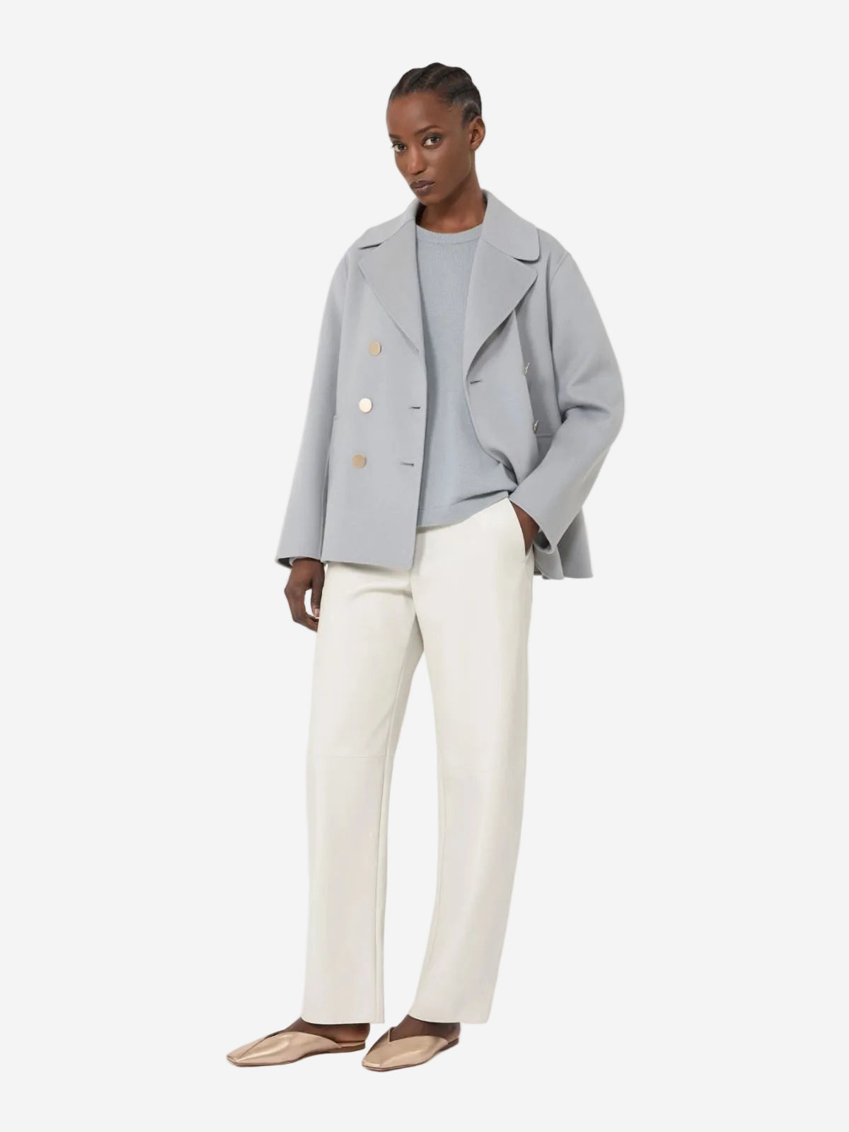 Woman wearing a light gray jacket with buttons and white pants on a white background