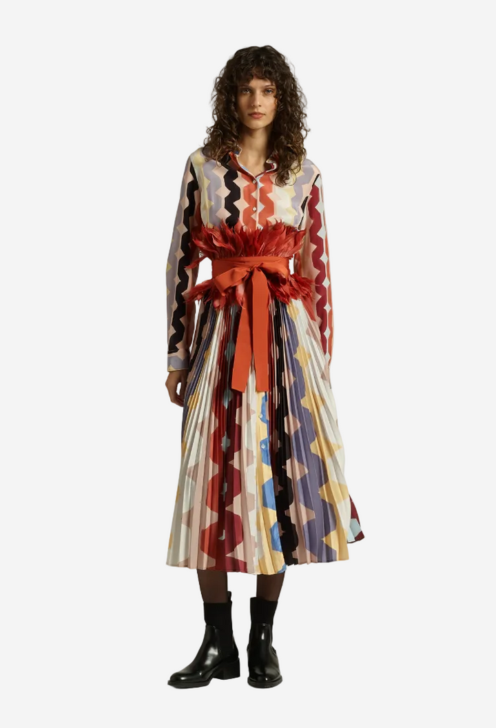Woman wearing a colorful patterned dress with a red belt on a white background