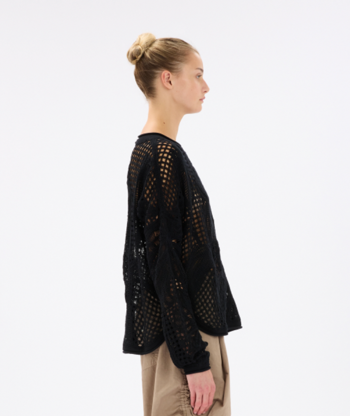 Woman wearing a black crochet sweater on a white background
