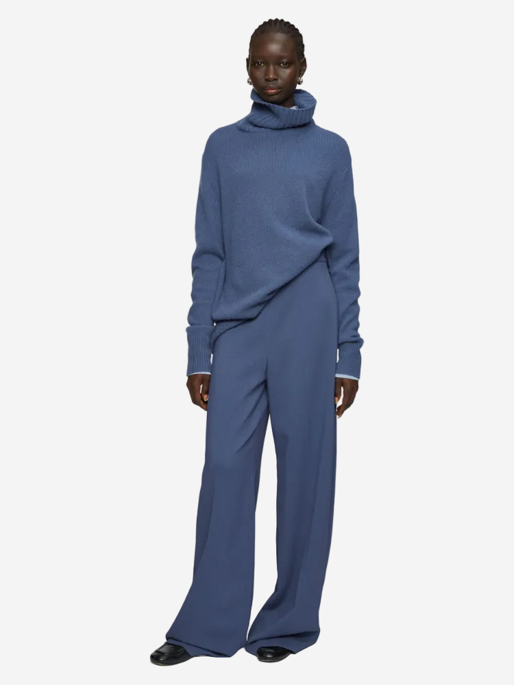 Person wearing a blue outfit with a turtleneck sweater and wide-leg pants on a white background