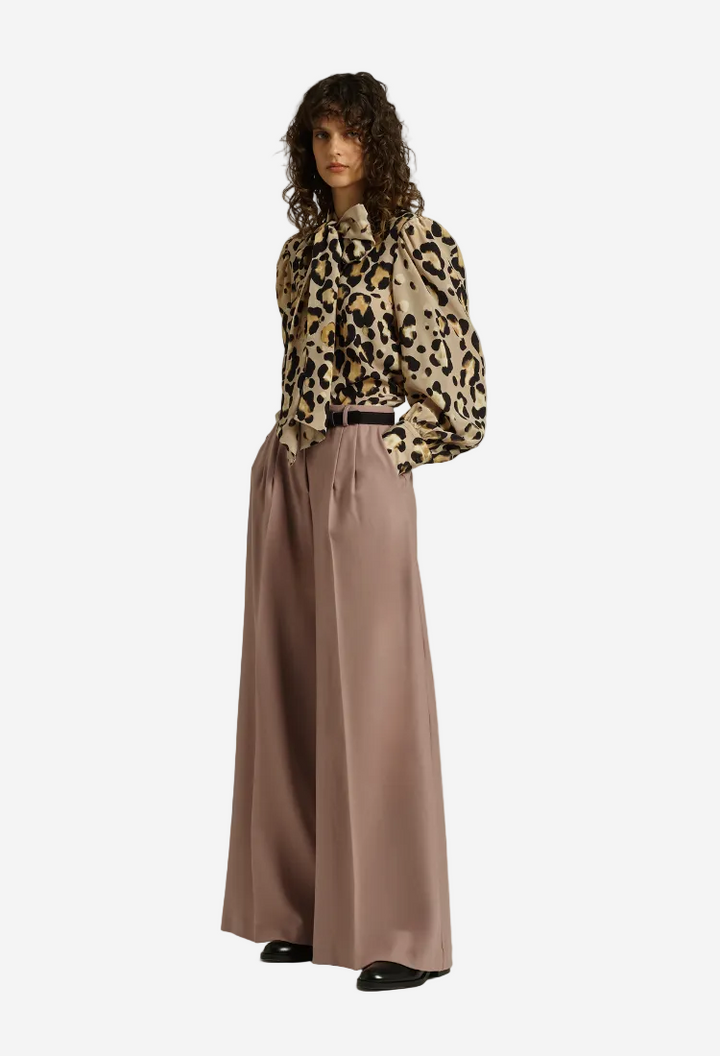 Woman wearing a leopard print blouse and wide-leg pants on a white background