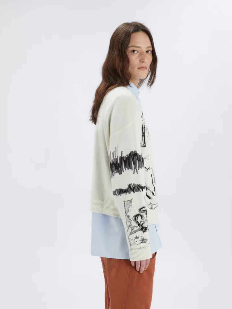 Person wearing a light-colored sweater with black abstract designs on a white background