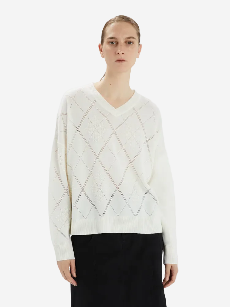 Person wearing a white sweater with a geometric pattern on a white background