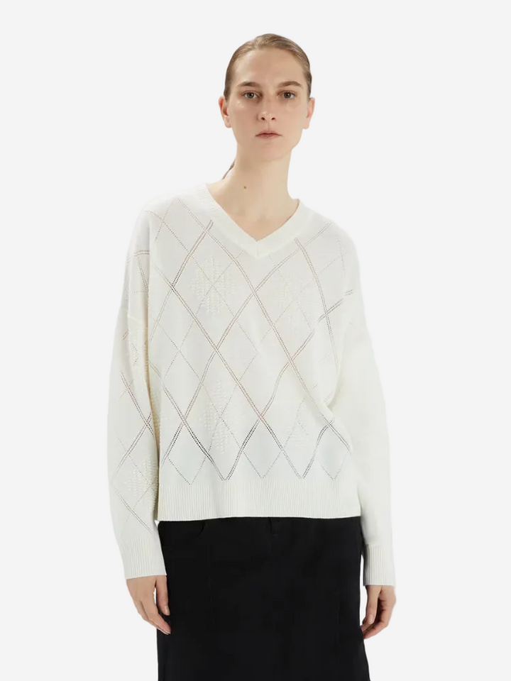 Person wearing a white sweater with a geometric pattern on a white background
