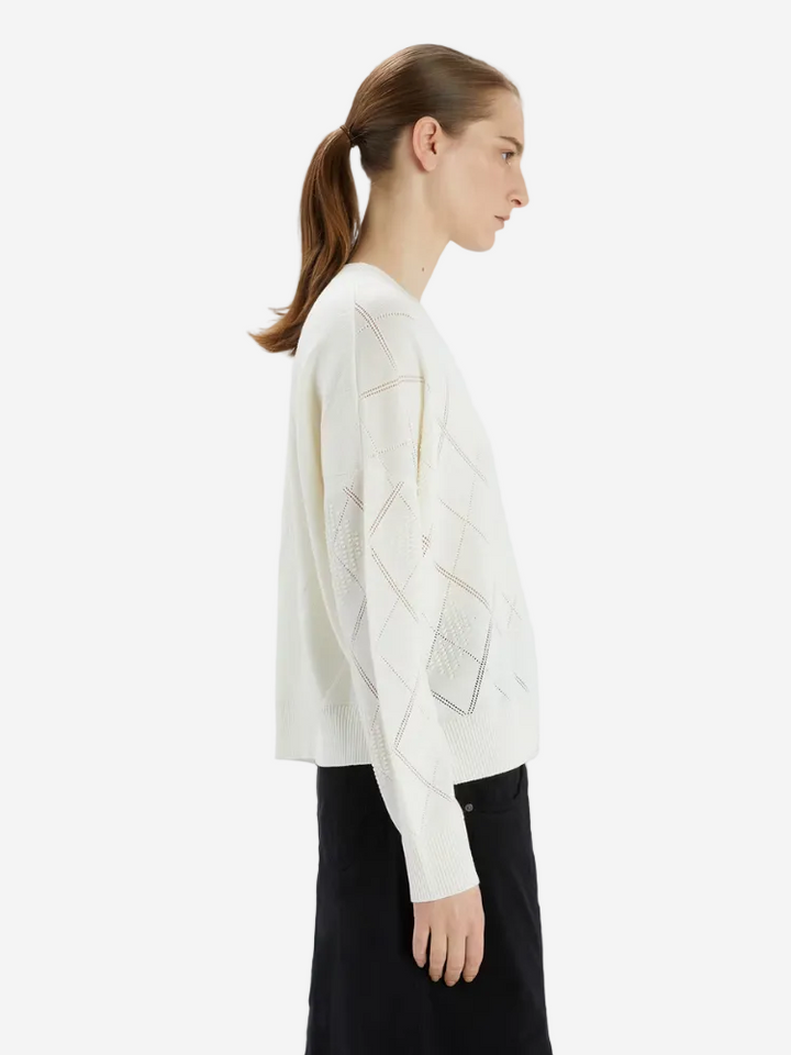Woman wearing a white sweater with geometric patterns on a white background