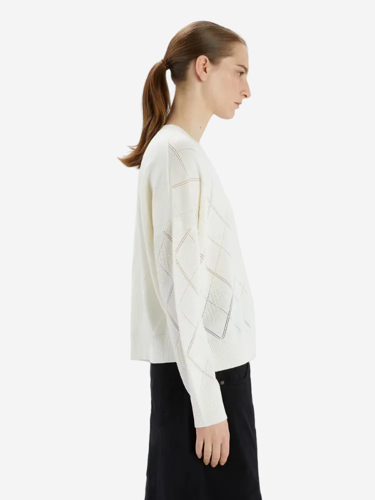 Woman wearing a white sweater with geometric patterns on a white background