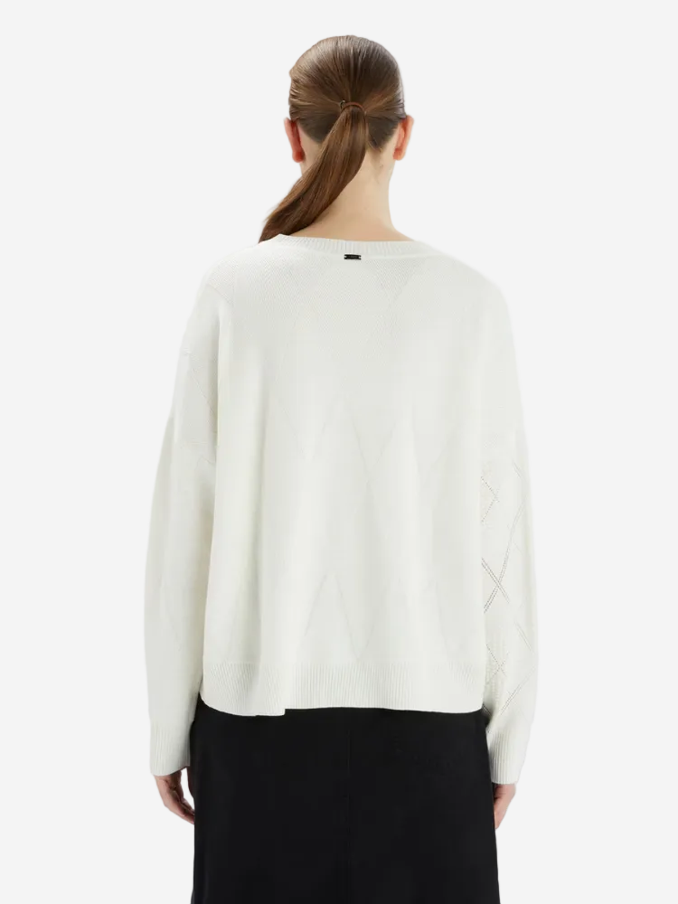 Person wearing a white sweater on a plain background