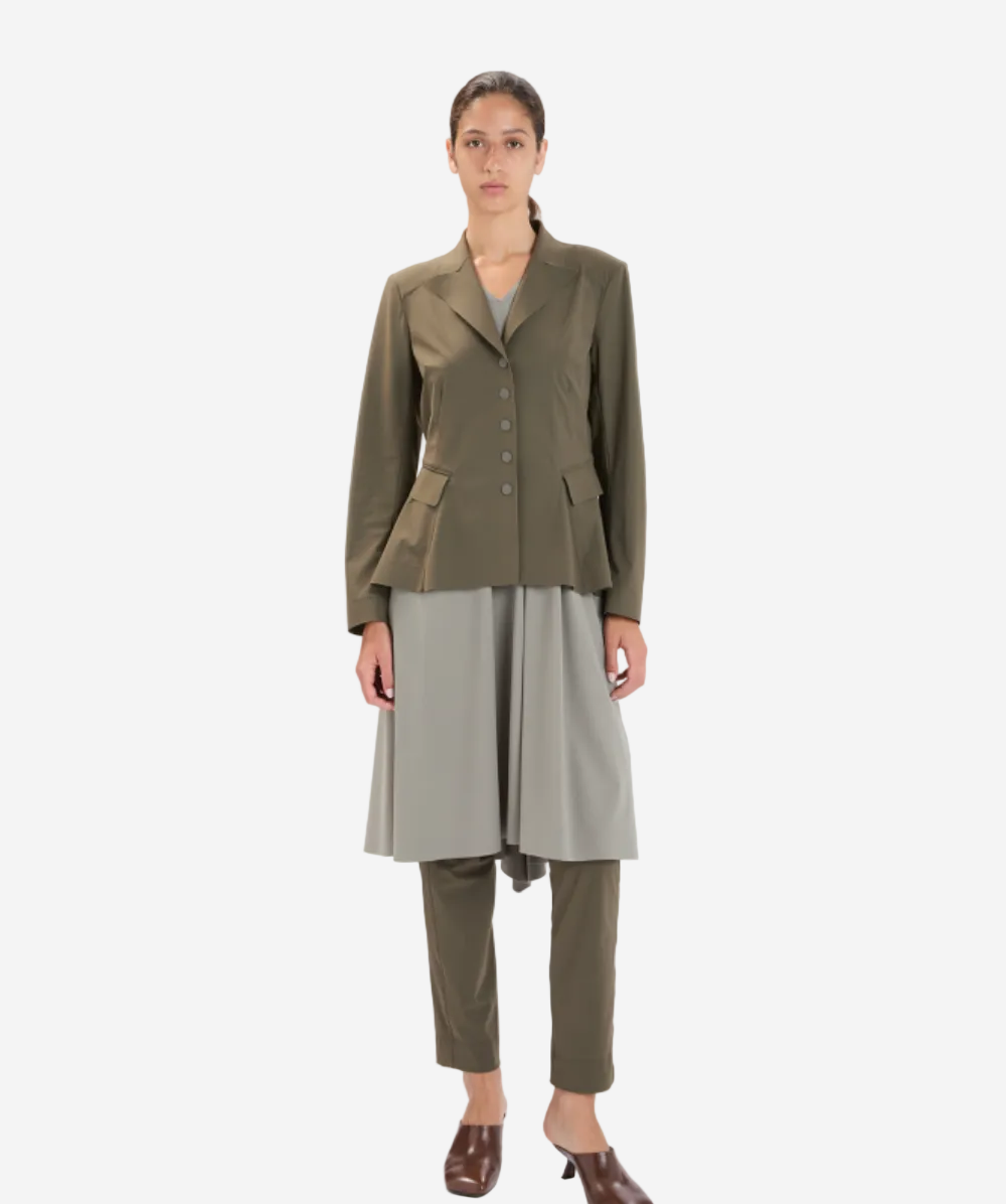Woman wearing a green jacket and gray skirt on a white background
