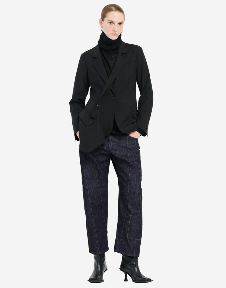 Person wearing a black coat, black turtleneck, and dark jeans on a white background