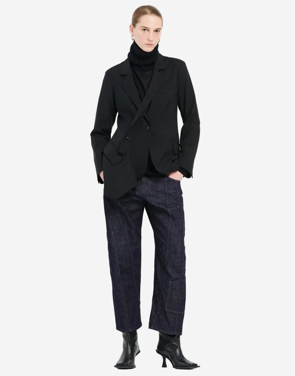 Person wearing a black coat, black turtleneck, and dark jeans on a white background