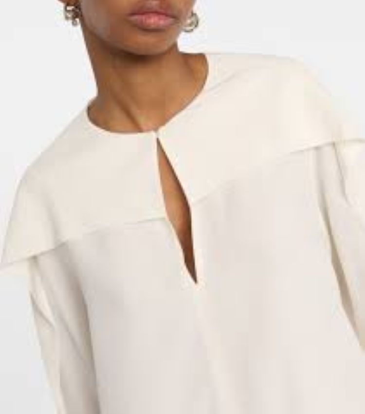 Close-up of a person wearing a white blouse with a cut-out design.