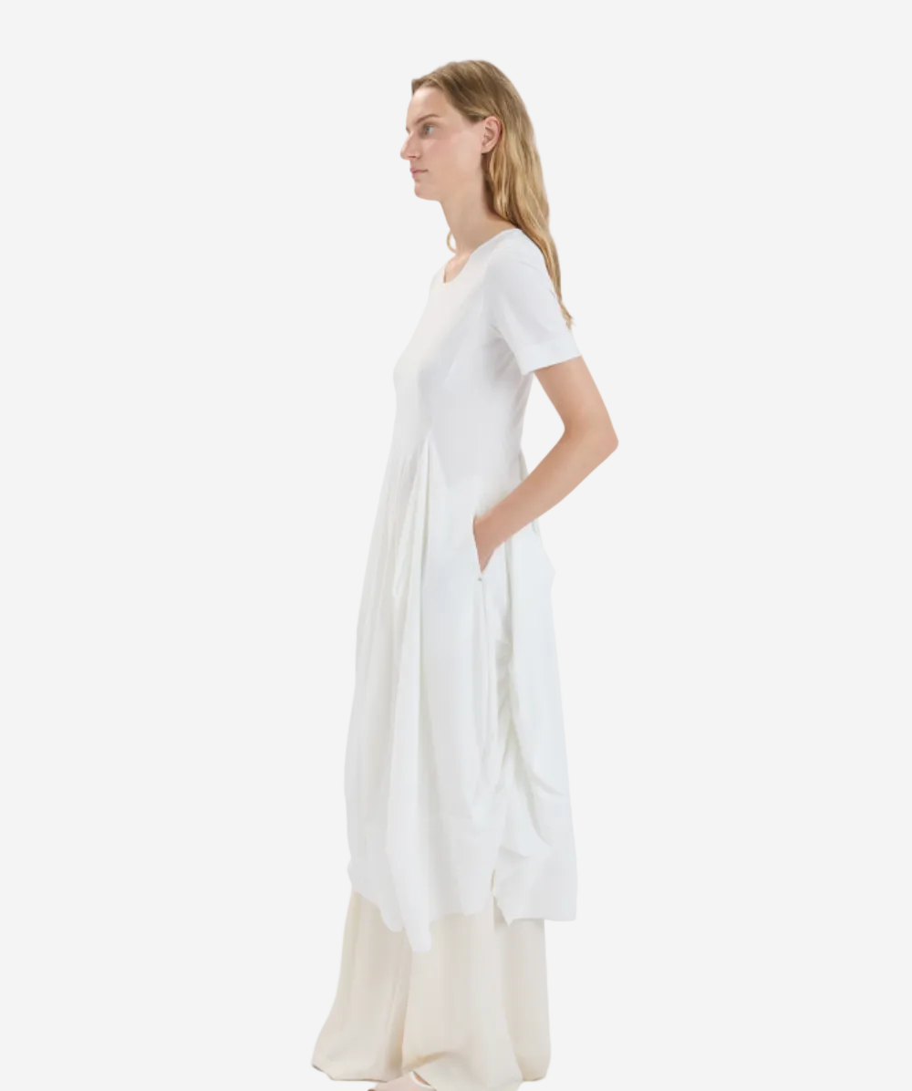 Woman wearing a long, light-colored dress against a white background