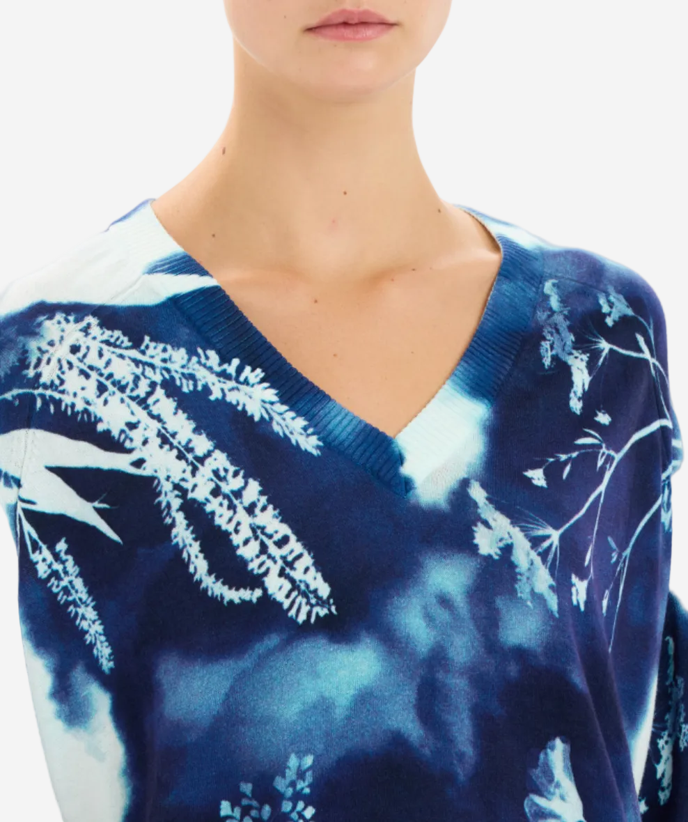Blue tie-dye sweater with white floral patterns on a plain background