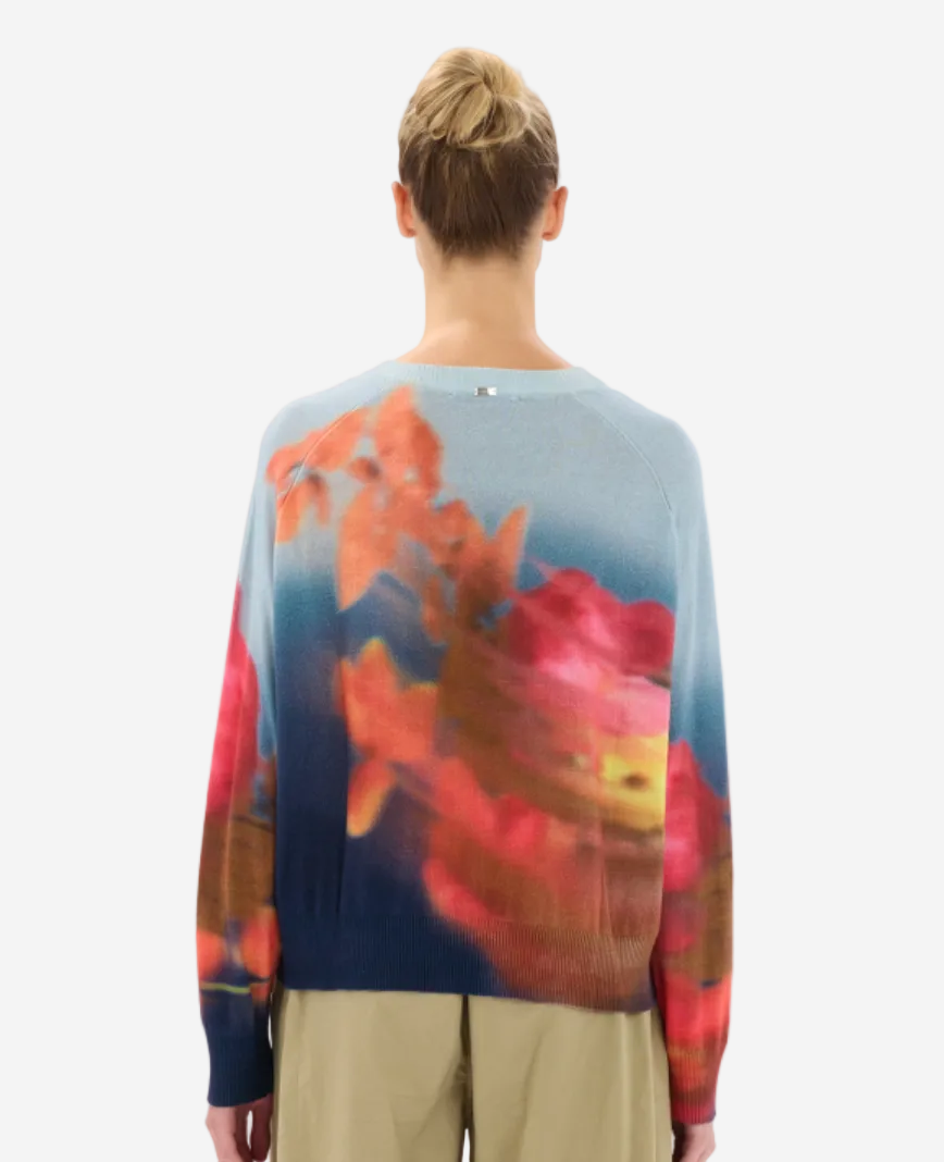 Person wearing a colorful sweater with abstract design on a plain background