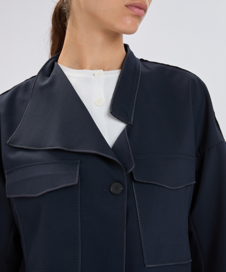 Navy blue coat worn by a person on a plain background