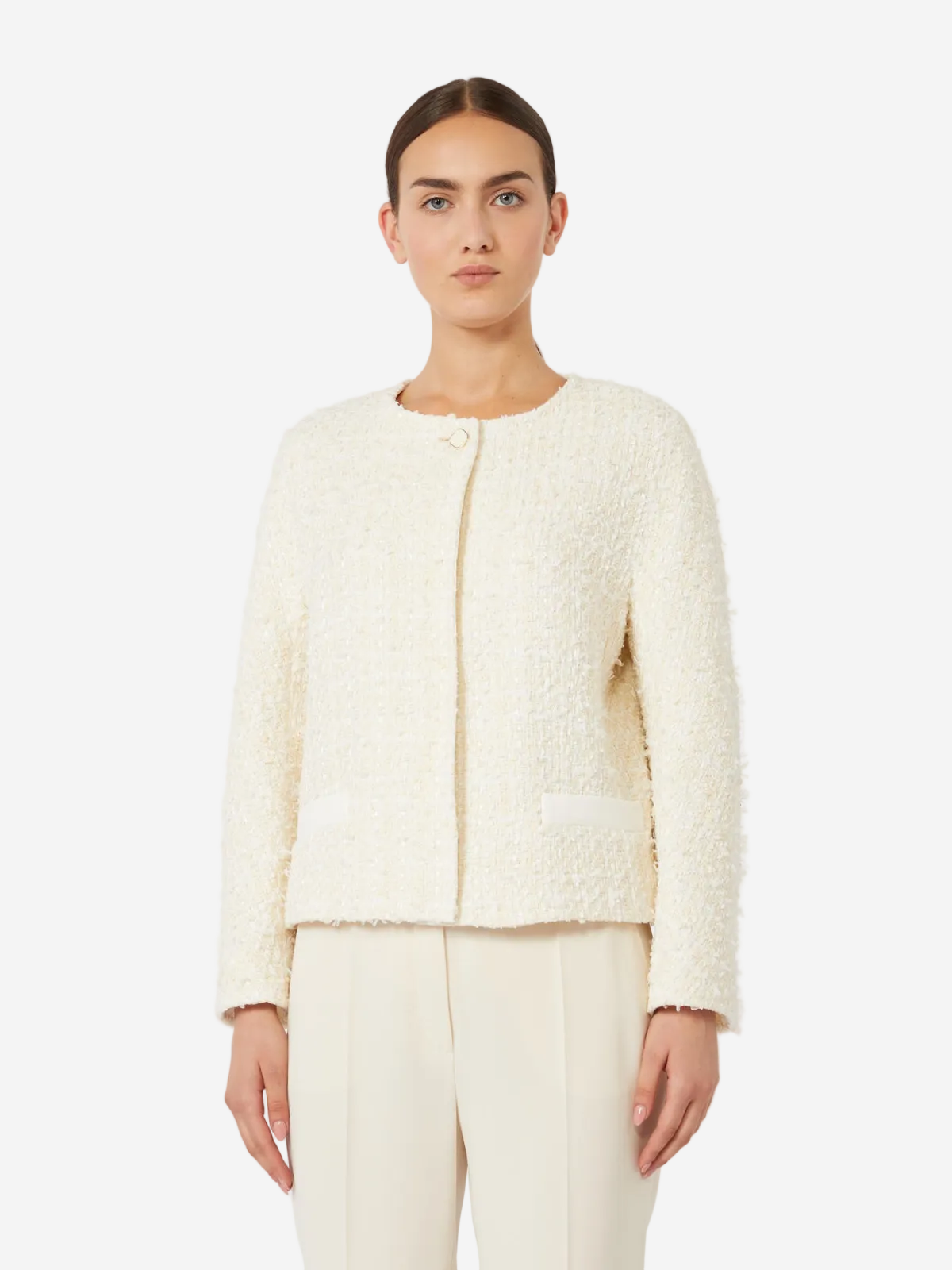 Woman wearing a cream-colored textured jacket and pants on a white background