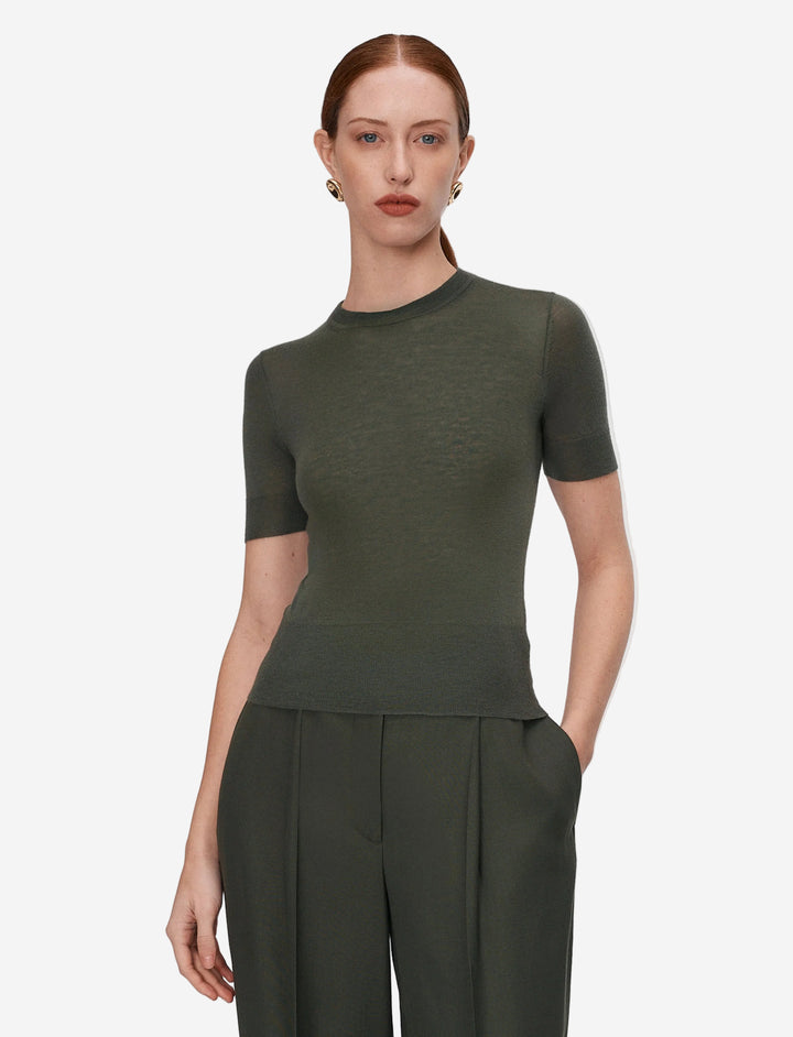 Woman wearing a green top and pants on a light gray background