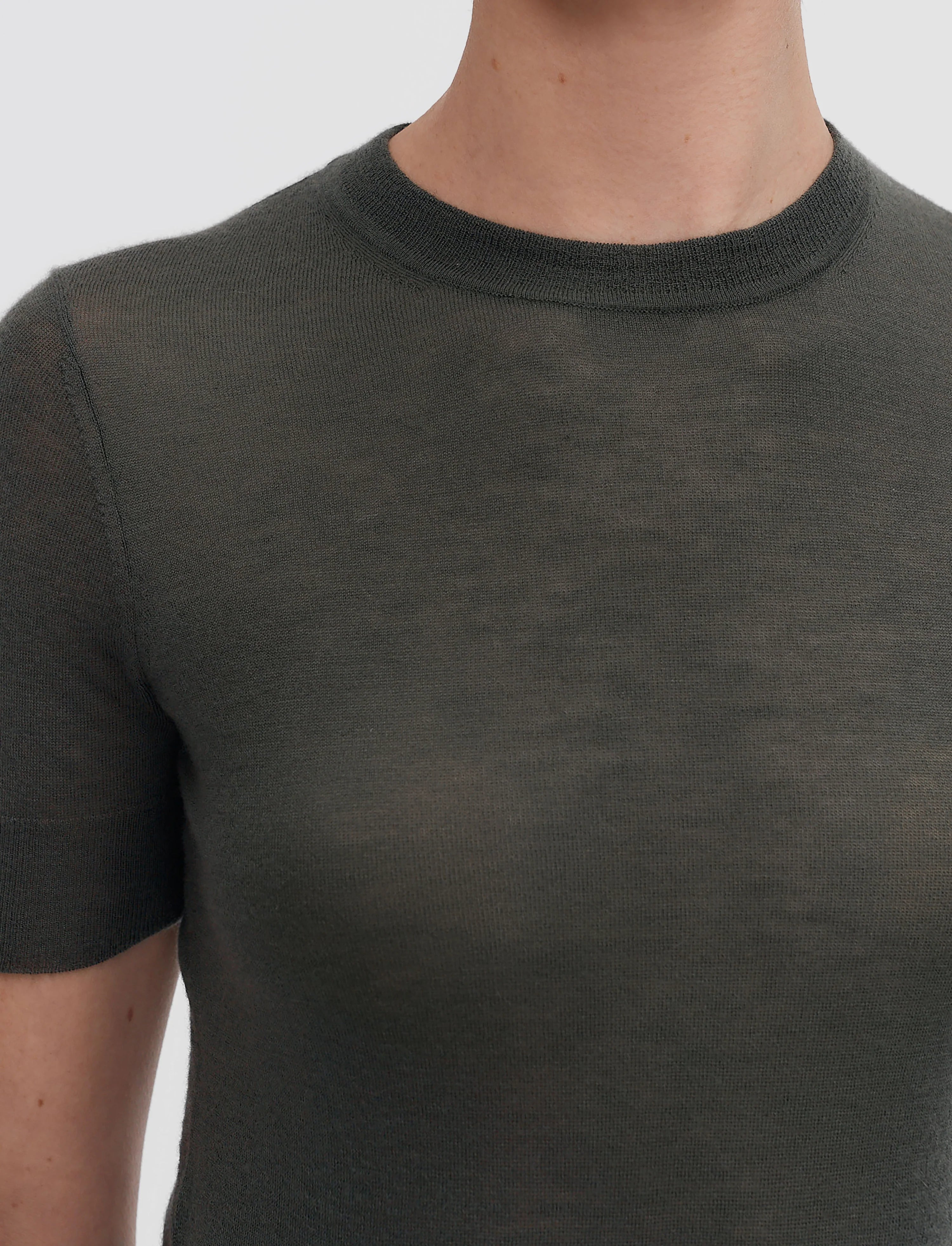 Person wearing a dark green t-shirt against a plain background