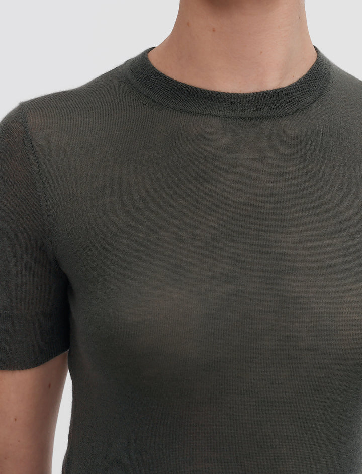 Person wearing a dark green t-shirt against a plain background
