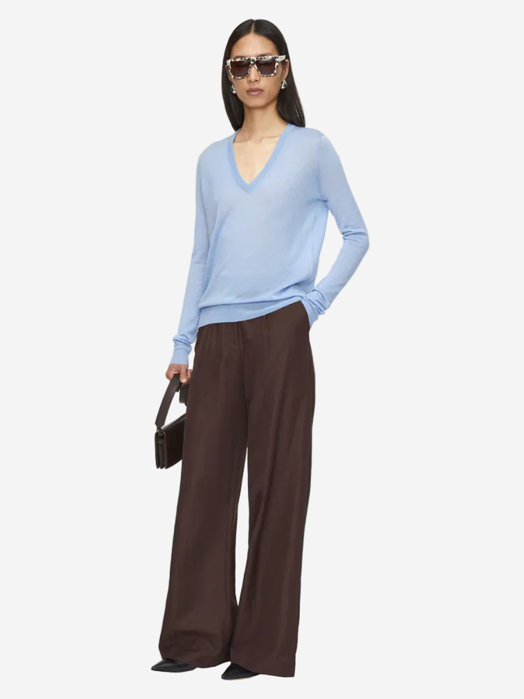 Woman wearing a light blue sweater and brown pants on a white background