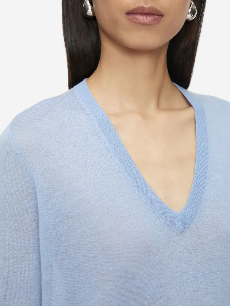 Close-up of a person wearing a light blue sweater with a V-neckline.