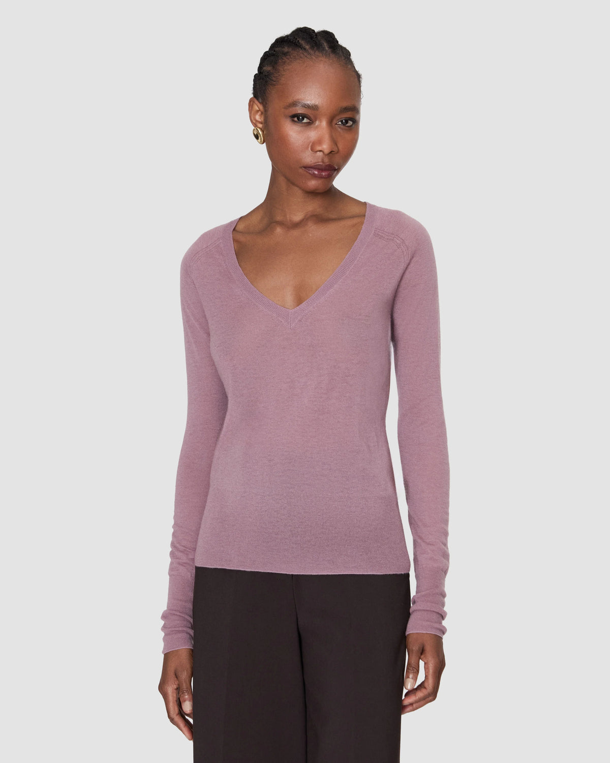 A model wearing a long-sleeve, v-neck knit sweater in a dusty mauve-pink colour from Christensen Copenhagen