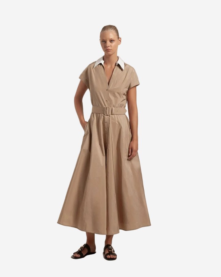 Woman wearing a beige dress with a belt on a plain background