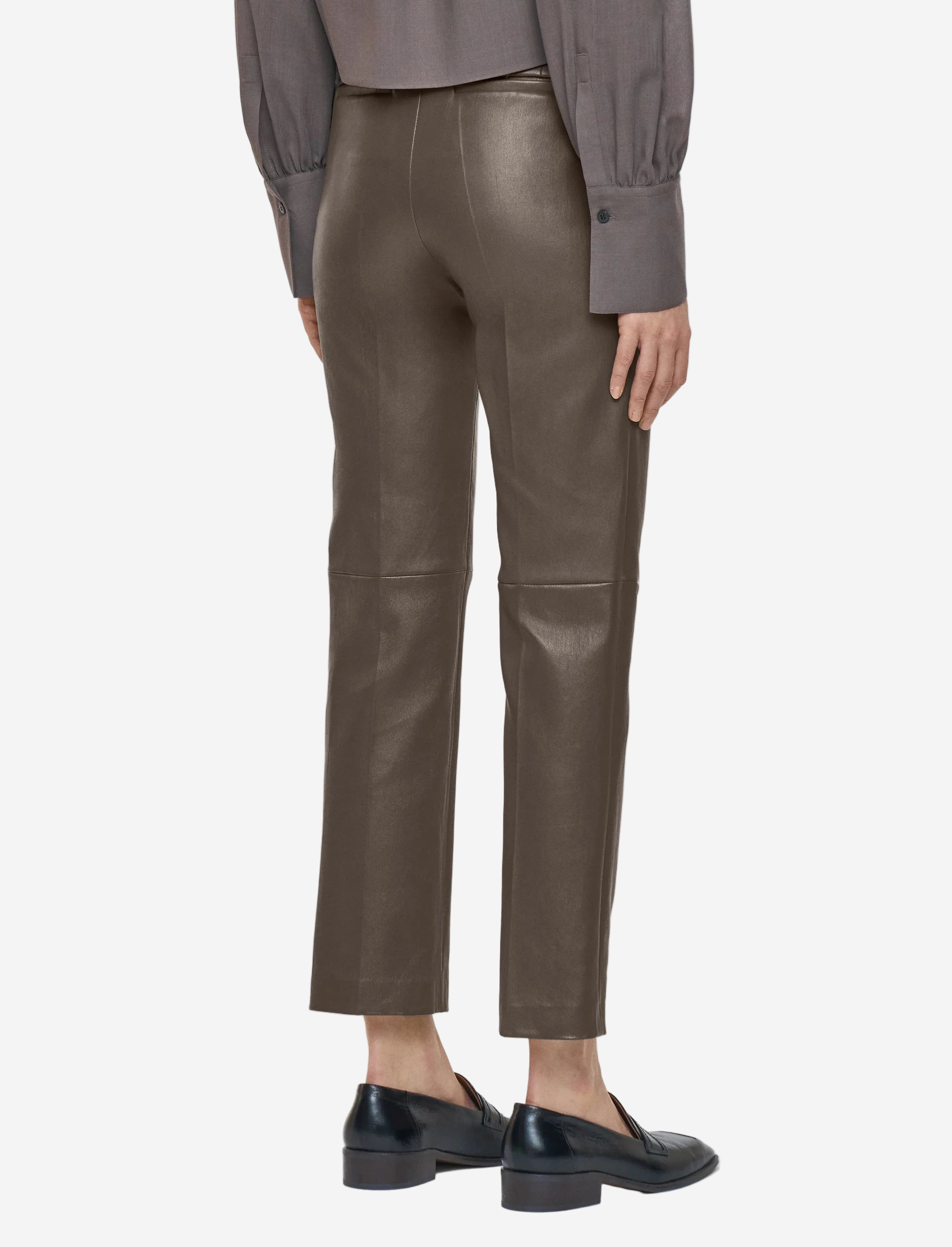 Person wearing brown leather pants on a white background