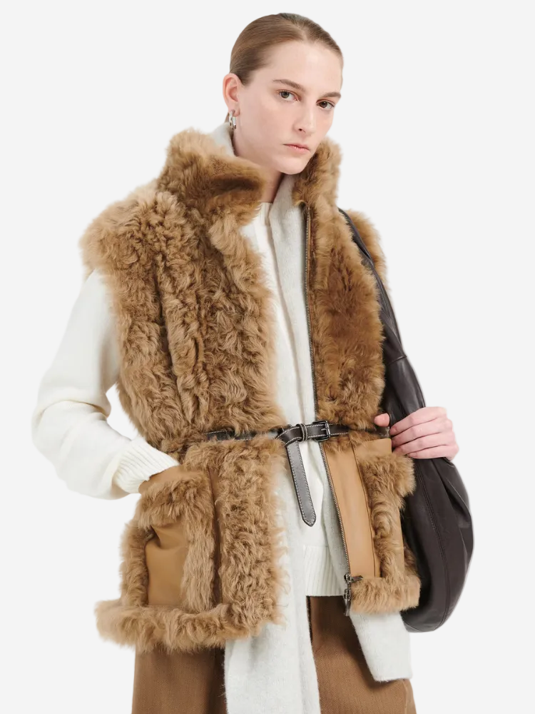 Woman wearing a brown fur vest over a white coat on a white background