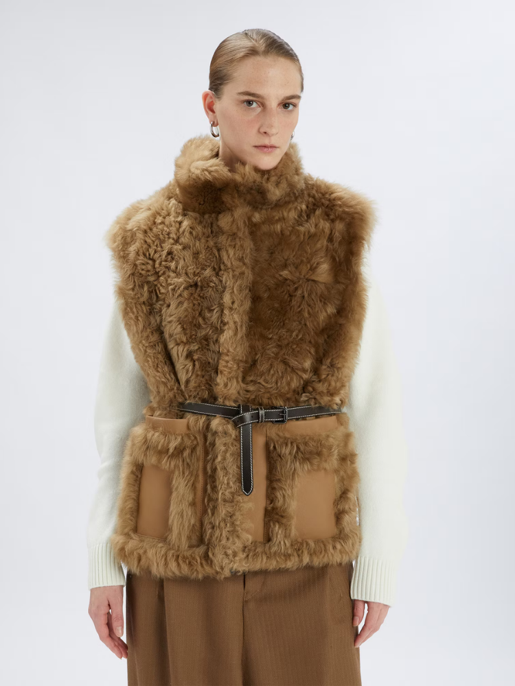 Person wearing a brown fur vest on a white background