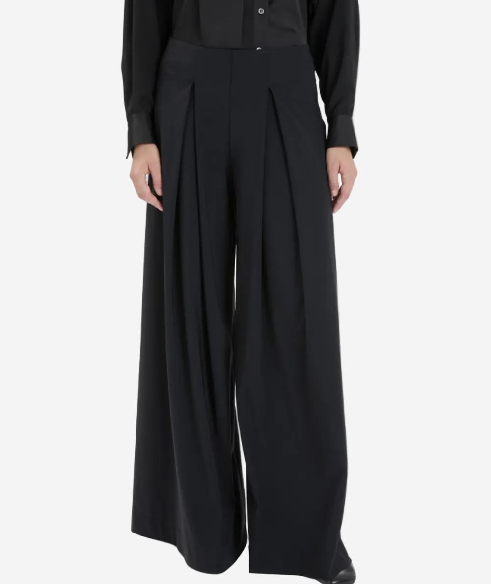 Person wearing a black outfit with wide-leg pants on a white background