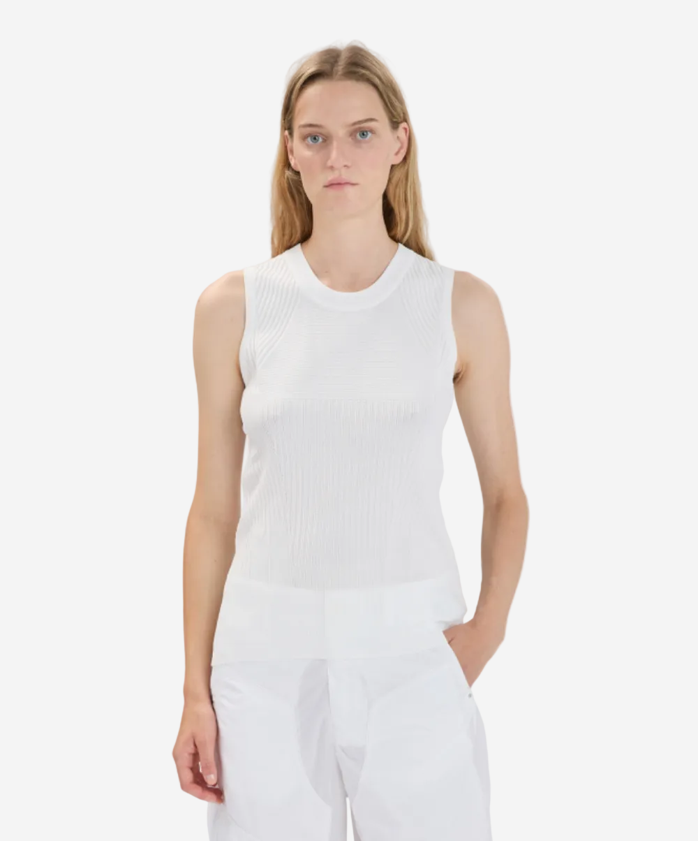 Person wearing a white sleeveless top and pants on a plain background