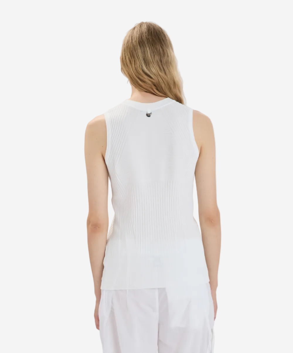 Person wearing a white sleeveless top and pants on a plain background