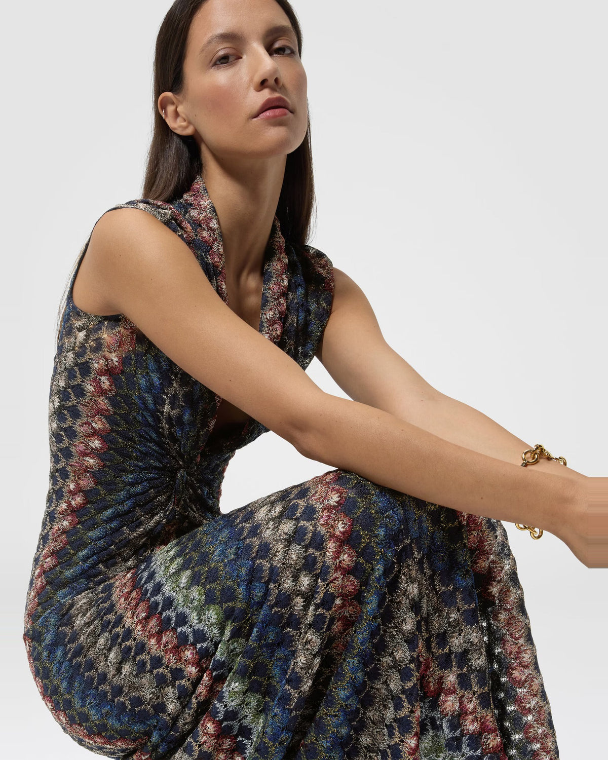 Model seated in the Missoni dark multicolour lamé lace dress showing the shimmering chevron pattern